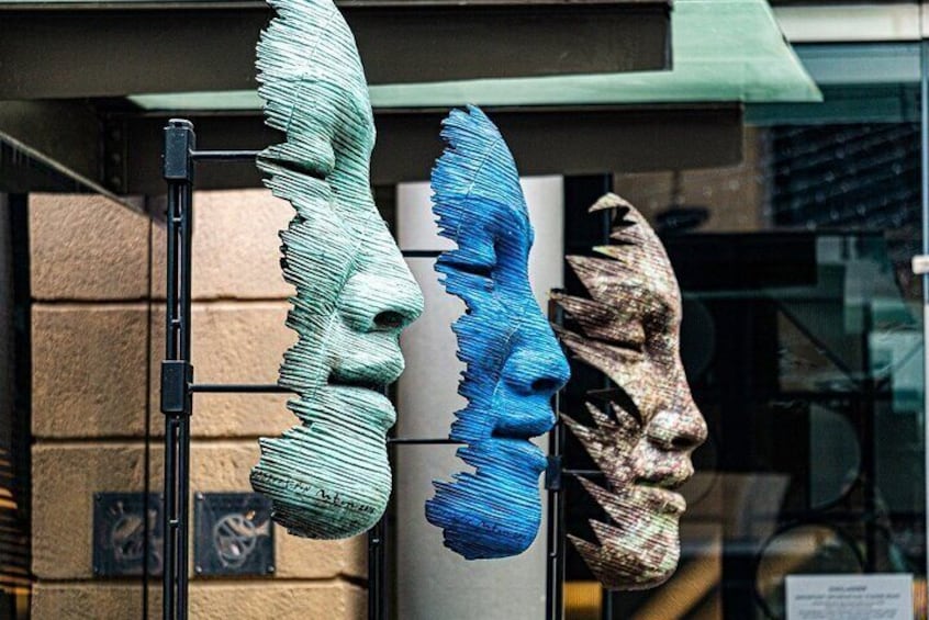 Three large, textured sculptures of faces mounted on a wall. 4