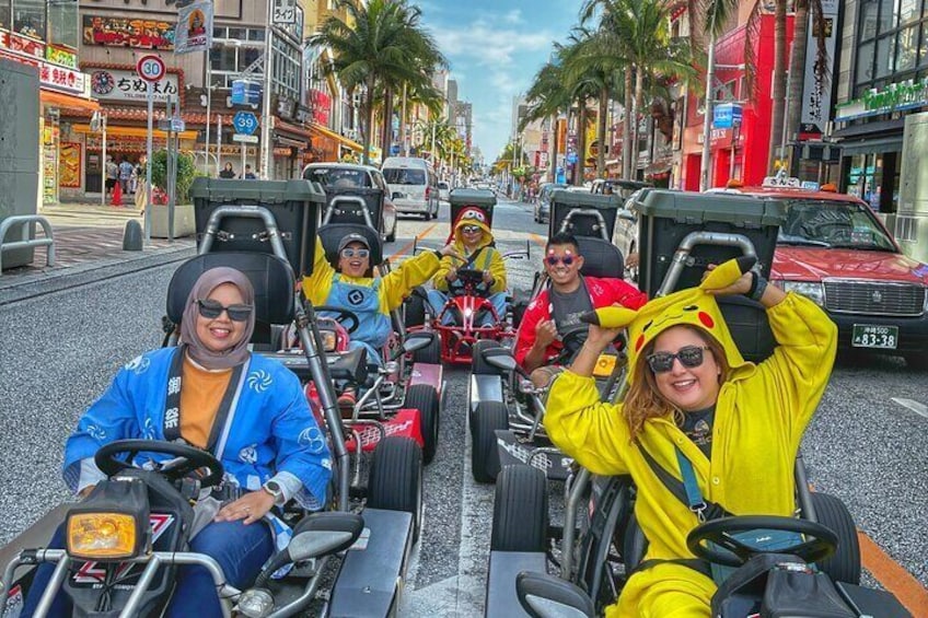 People in go-karts on a city street lined with palm trees and shops. 2