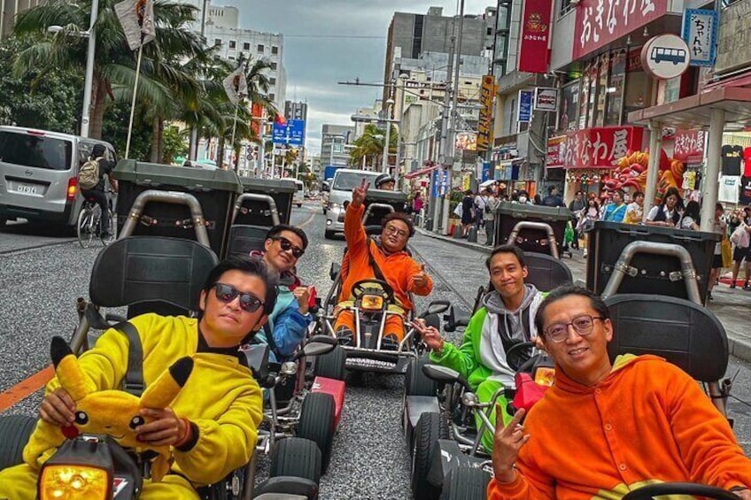 People in go-karts on a busy street with shops and palm trees. 3