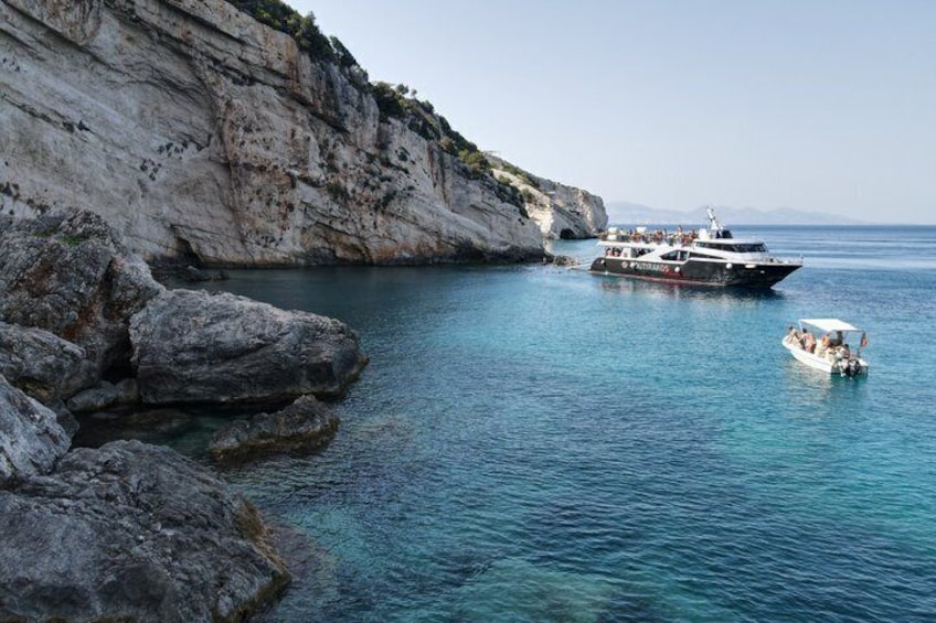 A coastal scene with a boat near rocky cliffs and calm blue waters. 2