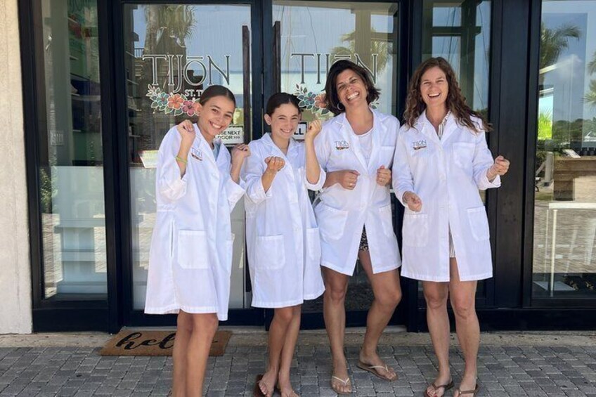 Four individuals in white lab coats standing in front of a storefront with a glass door. 1