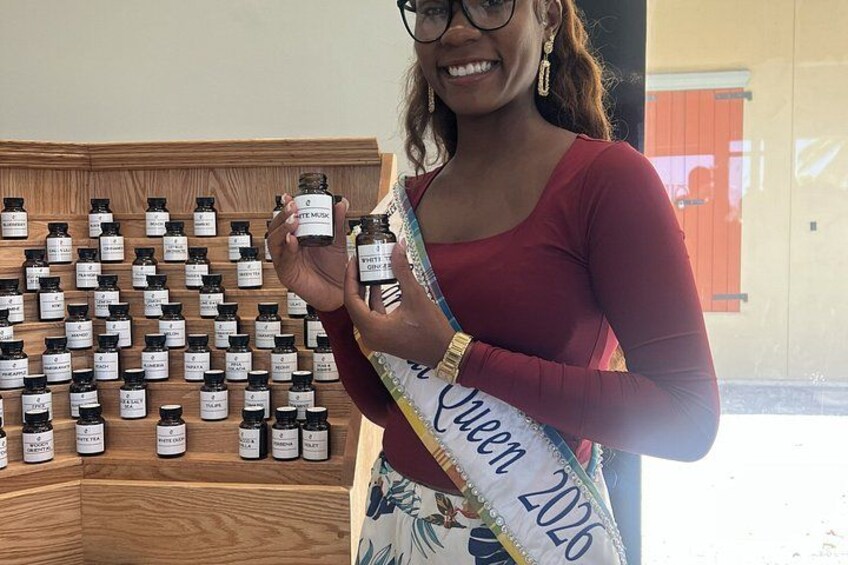 A person holding a bottle of essential oil with a display of various bottles behind them. 2