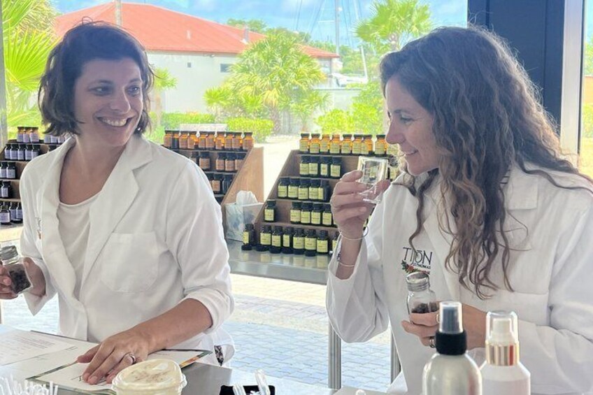 Two people at a table with bottles and a menu, in a store with shelves of products in the background. 3