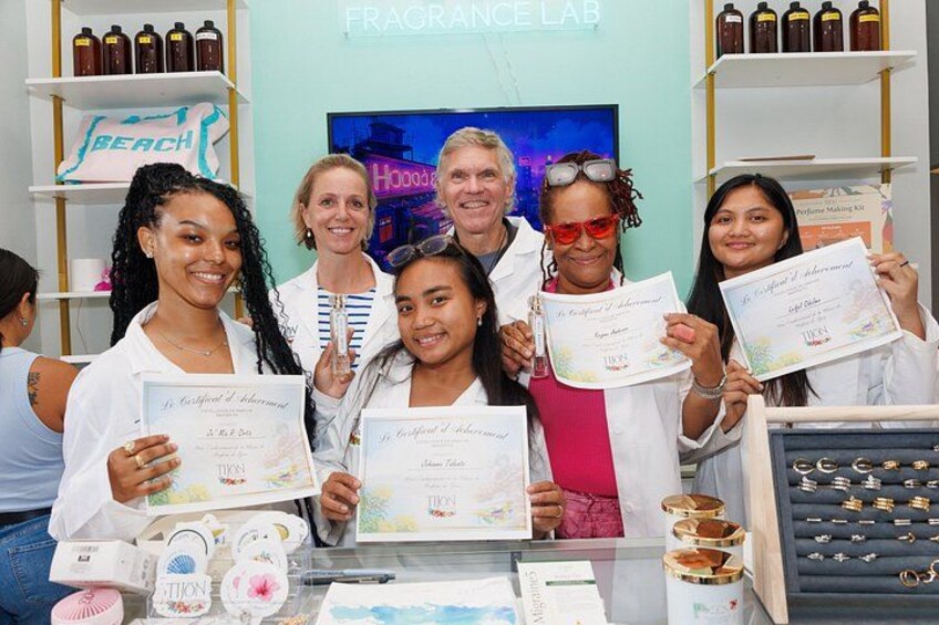 A group of people holding certificates in a store with shelves of bottles and jewelry. 2