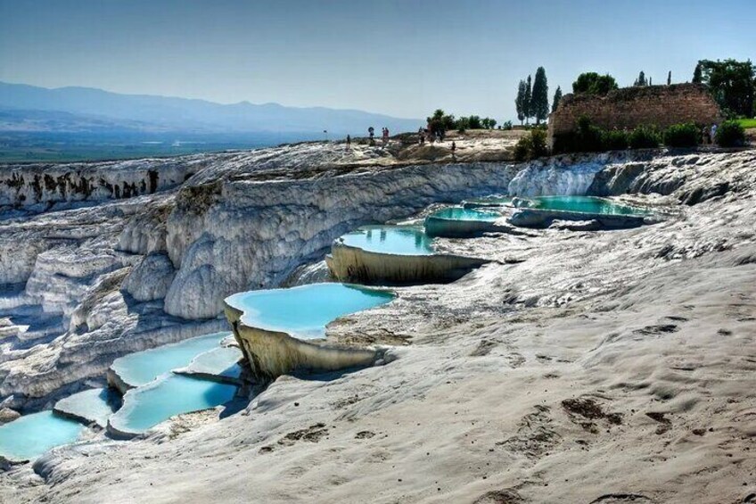 Terraced pools with clear blue water, a rocky landscape, and distant mountains. 2