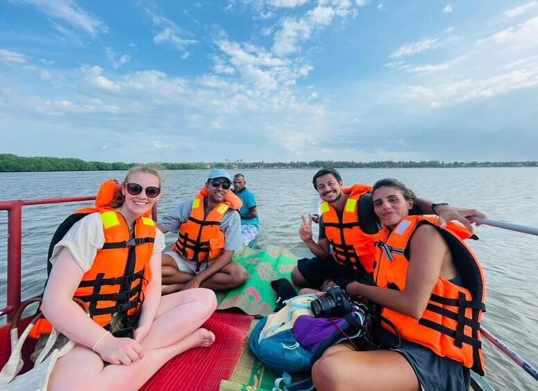 A group of people on a boat wearing life jackets, with a calm lake and trees in the background. 3