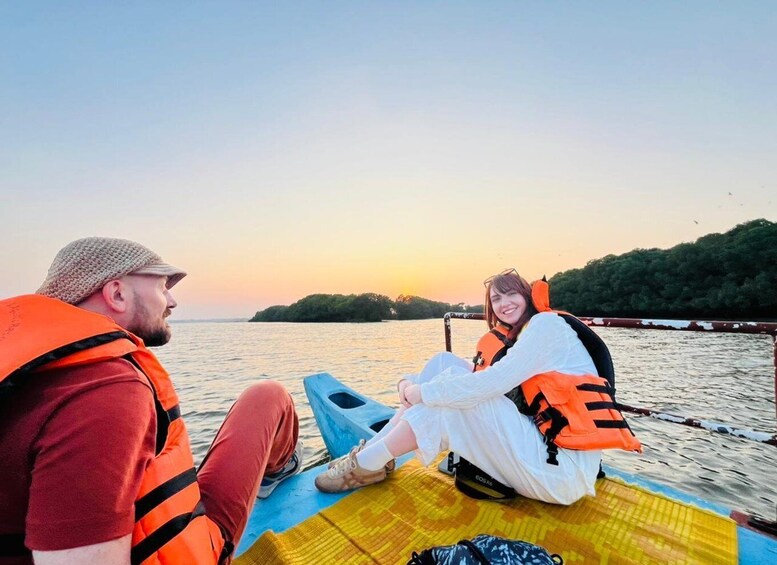 Two people on a boat with life jackets, a calm body of water, and a sunset in the background. 1