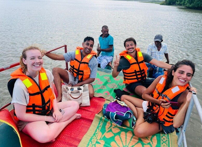 A group of people on a boat, wearing life jackets, with a river and greenery in the background. 3