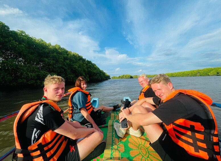 A group of people on a boat, wearing life jackets, on a river surrounded by greenery. 2