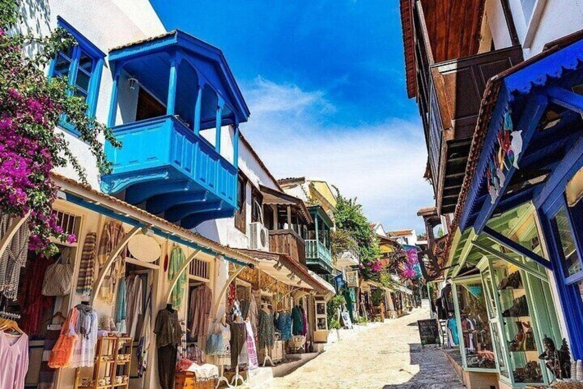 A narrow street with colorful buildings, balconies, and hanging plants. 4