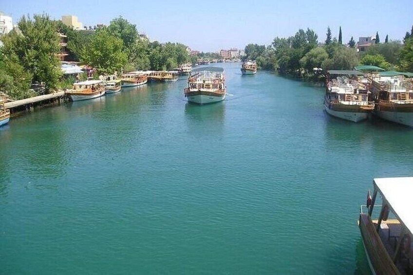 A river with boats docked along the banks, surrounded by greenery and buildings. 5