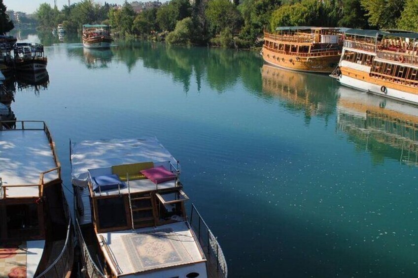 A calm river with boats docked along the banks. 3