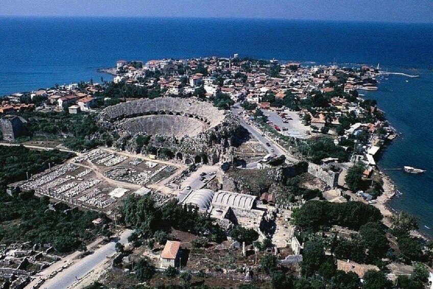 An ancient amphitheater surrounded by a coastal town with a clear view of the sea. 4