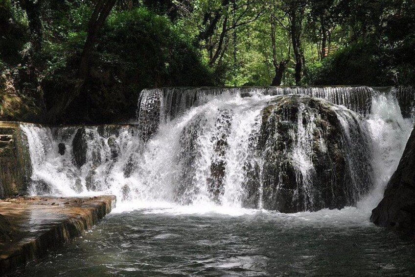 A waterfall cascading over rocks in a forested area. 2