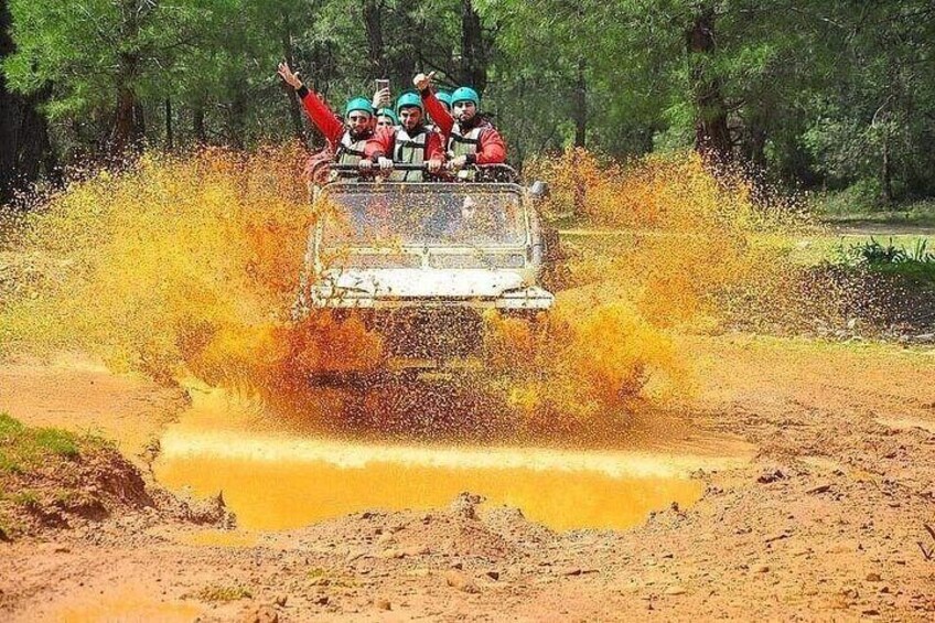 A vehicle driving through a muddy area, kicking up mud. 2