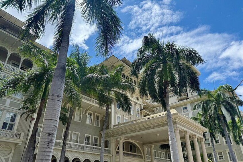 A multi-story building with a balcony, palm trees, and a clear sky. 4