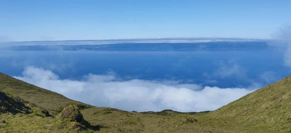 A coastal landscape with rolling hills, a clear sky, and a view of the ocean below. 3