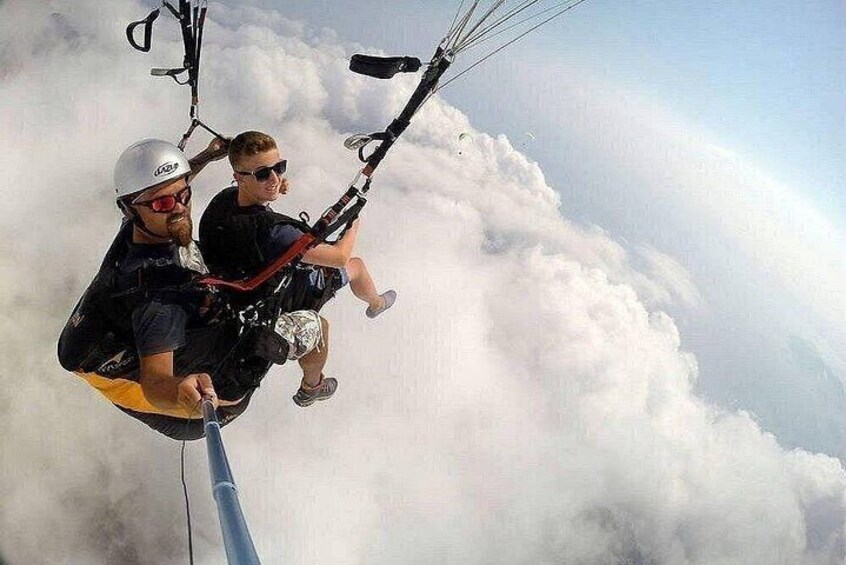 Two people paragliding above clouds. 1