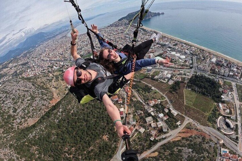 Two people paragliding over a coastal city with a view of the sea and urban landscape below. 2
