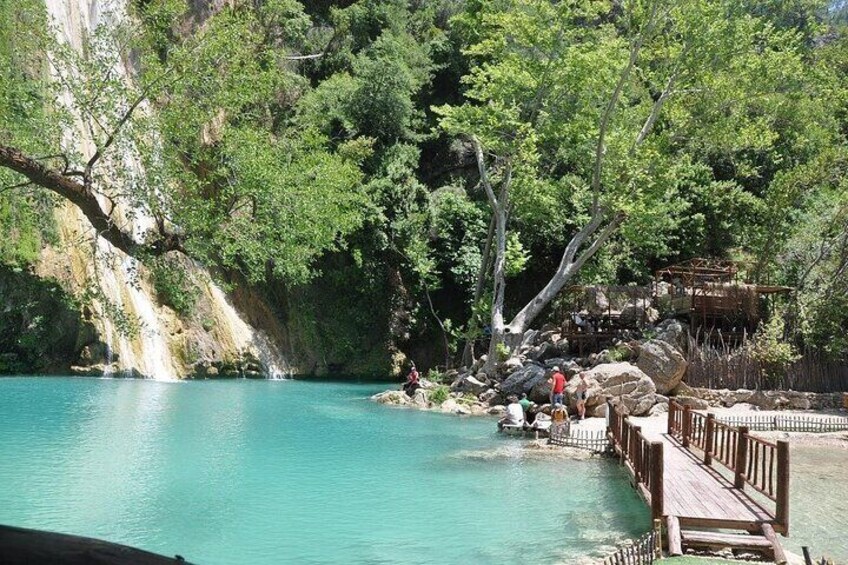 A turquoise lake surrounded by trees, a wooden deck, and a rocky cliff. 2