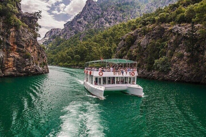 A boat with passengers on a river surrounded by cliffs. 1
