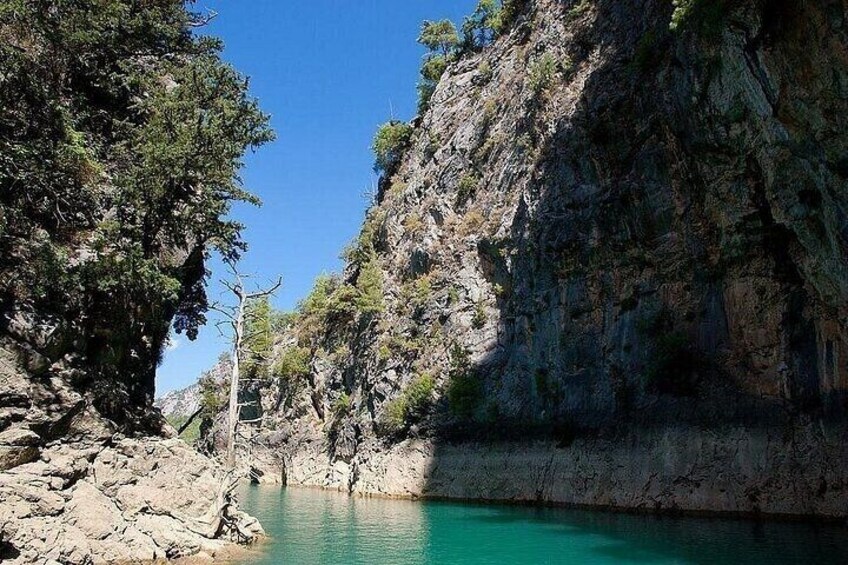 A turquoise river, rocky cliffs, and sparse vegetation. 5