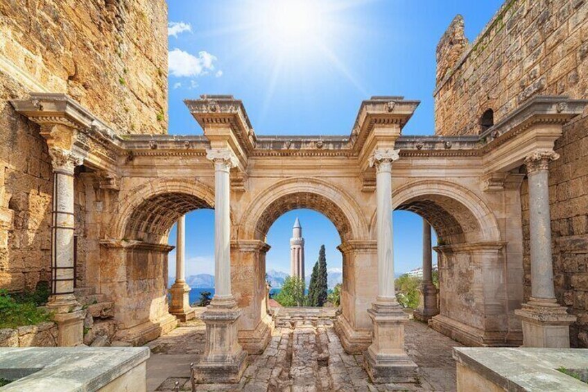 Ancient ruins with arches and columns, a distant minaret, and a clear sky. 1
