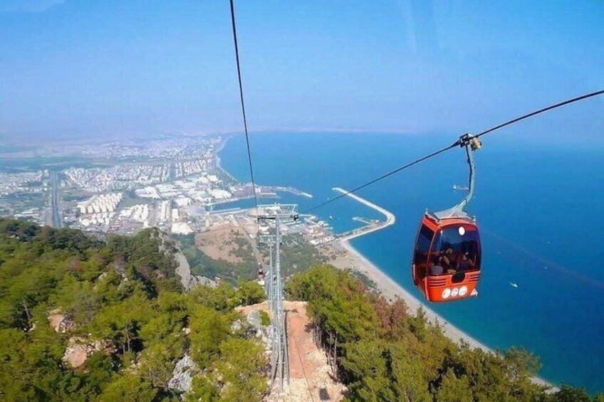 A cable car over a coastal city with a clear view of the sea and a bridge in the distance. 3