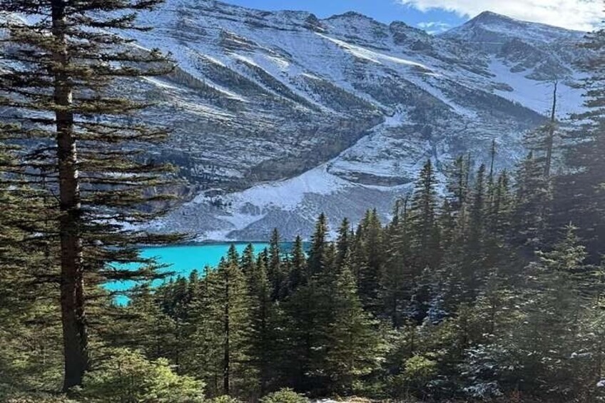 A mountain landscape with snow-covered peaks, a turquoise lake, and dense coniferous forest. 5