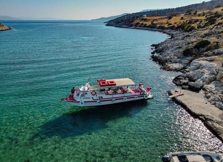 A boat named 'EIPHN' on a clear blue sea near rocky shores. 2