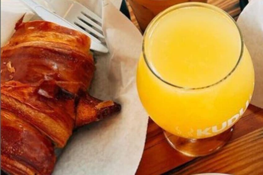 A croissant and a glass of orange juice on a wooden table. 5