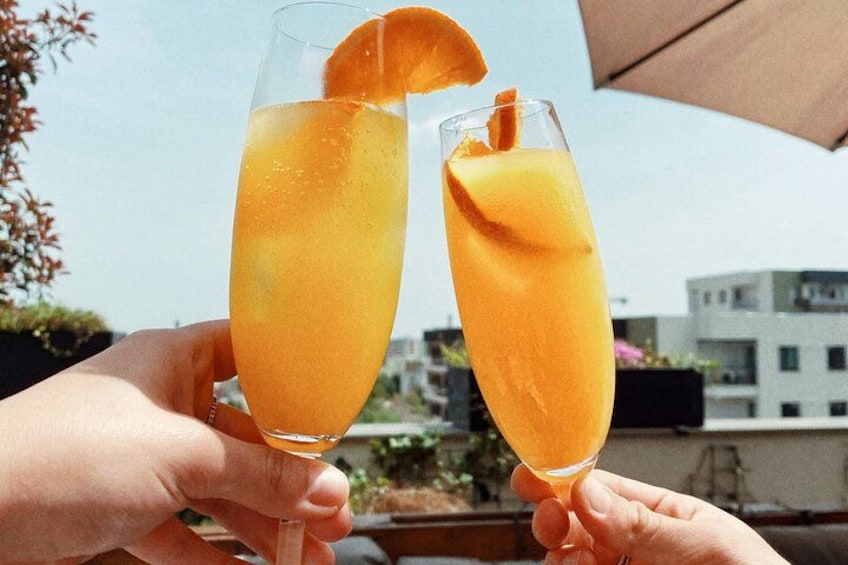 Two hands holding tall glasses of orange juice with a slice of orange. 5