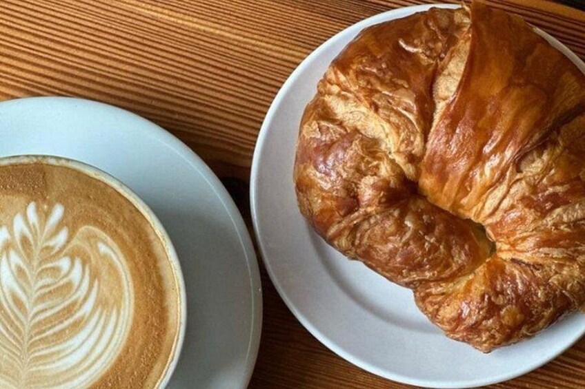 A croissant and a cup of coffee on a wooden table. 1