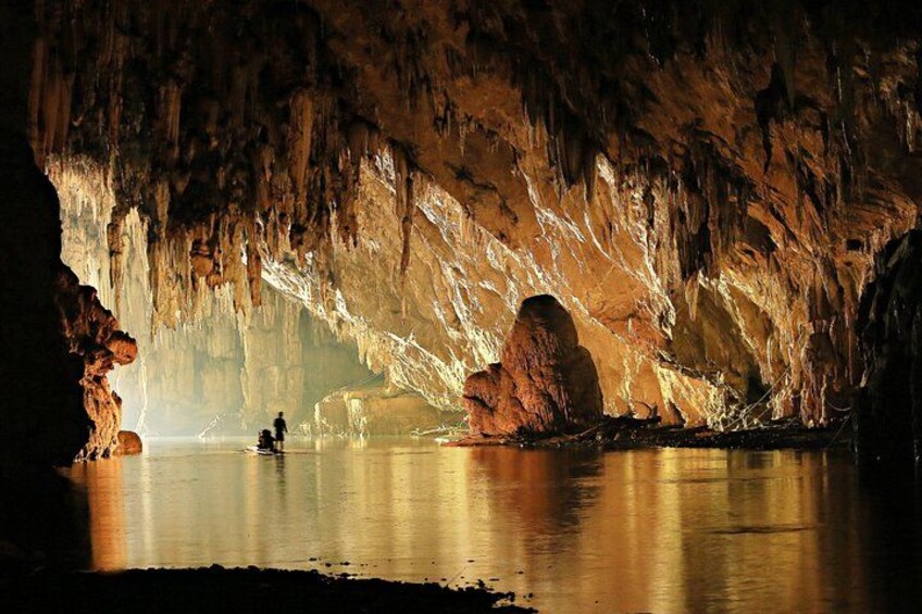 A cave with stalactites and stalagmites, a person fishing, and a calm body of water. 2