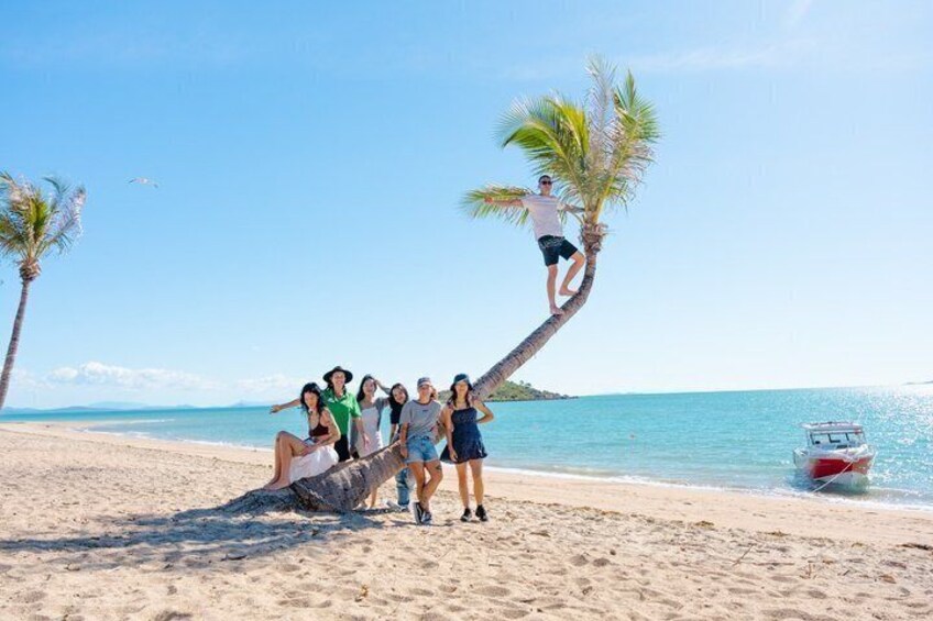A group of people on a beach with a boat in the water. 1