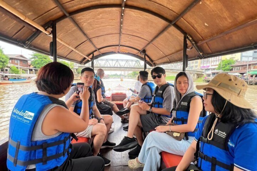 A group of people on a boat wearing life jackets and engaging in conversation. 1