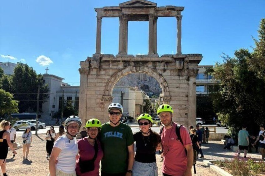 A group of people in front of an ancient archway with columns. 1