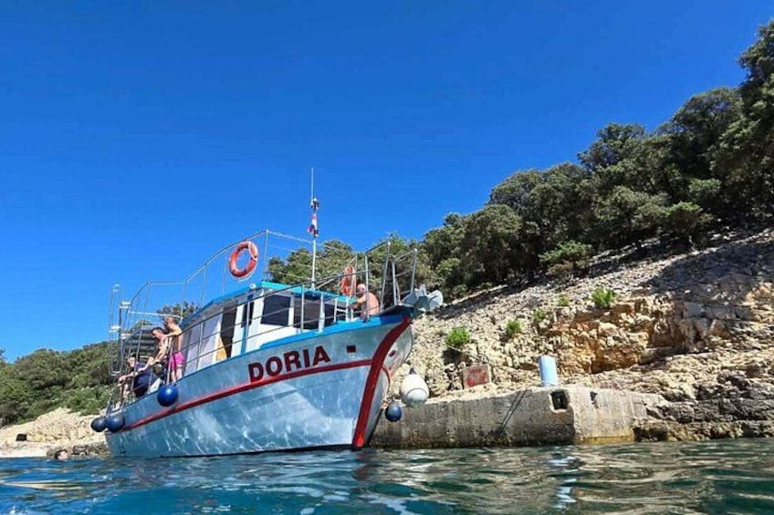 A boat named DORIA docked near a rocky shoreline with trees in the background. 3