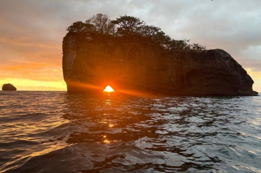 Un atardecer sobre una gran formación rocosa con agua al frente. 5