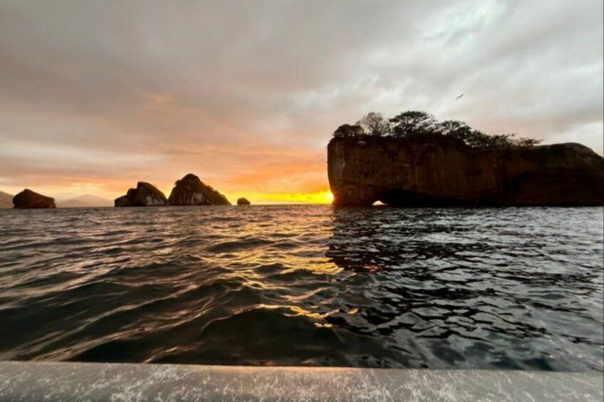 Un atardecer sobre el océano con grandes formaciones rocosas. 3