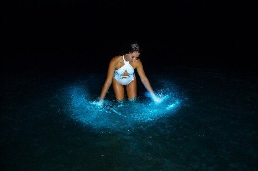 A person in a swimsuit standing in water with splashes around them. 3