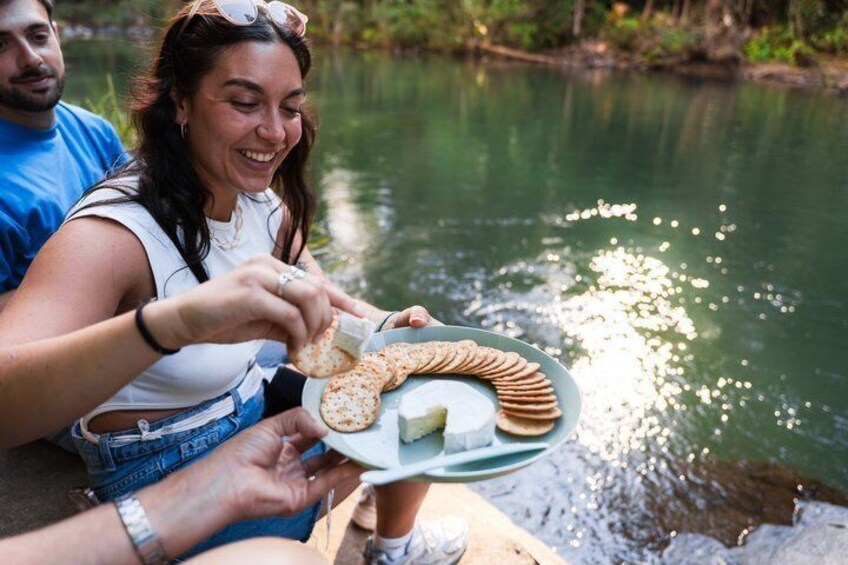 A person holding a plate with snacks by a body of water. 5