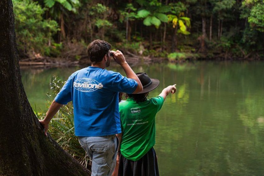 Two people standing by a river, one pointing towards the water. 2