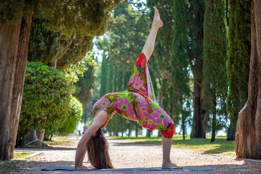 A person performing a yoga pose in a park with trees and a clear sky. 5