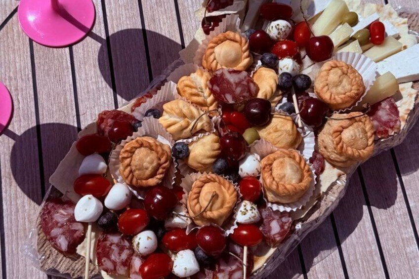 A charcuterie board with various cheeses, fruits, and pastries on a wooden table. 4