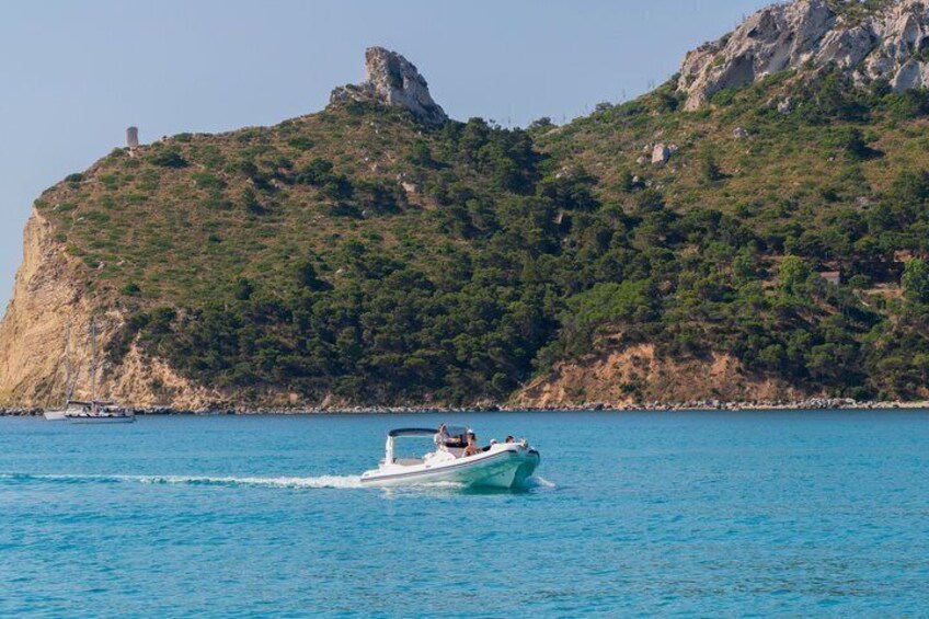 A boat on a calm sea with a rocky hill in the background. 2