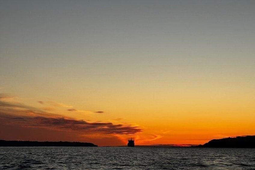 A sunset over a body of water with a distant landmass and a solitary structure. 3