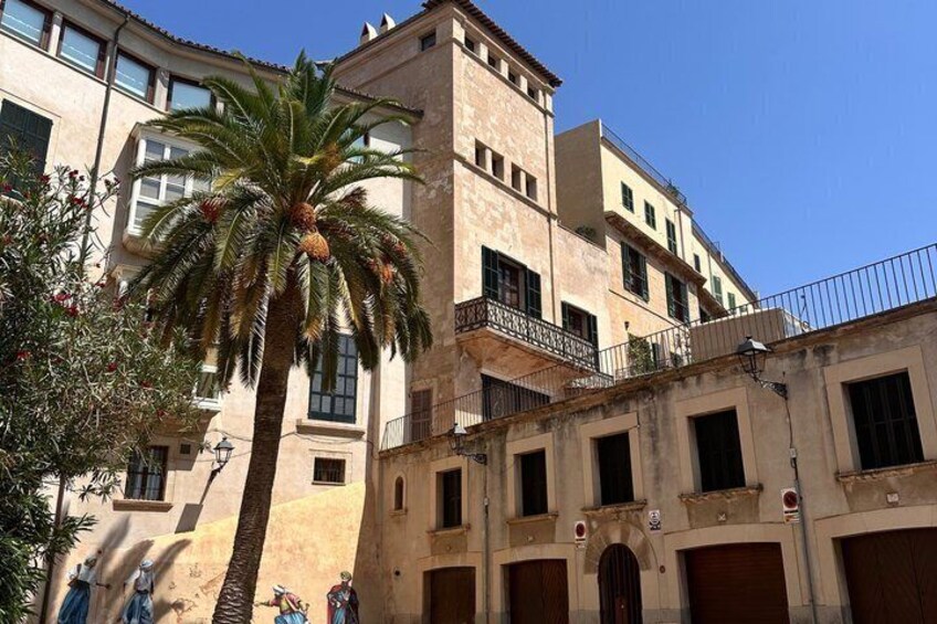 A historic building with a palm tree, balconies, and a clear blue sky. 2