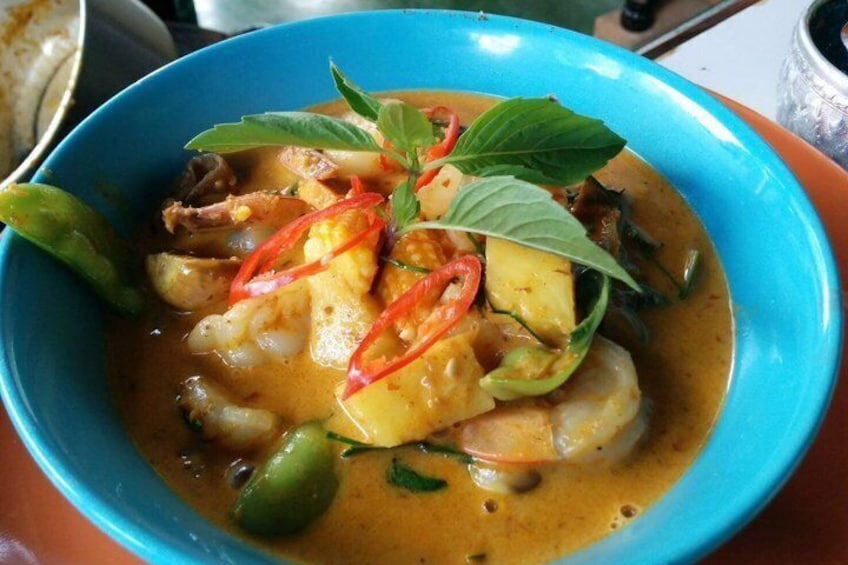 A bowl of Thai curry with green beans, red chili, and basil. 2
