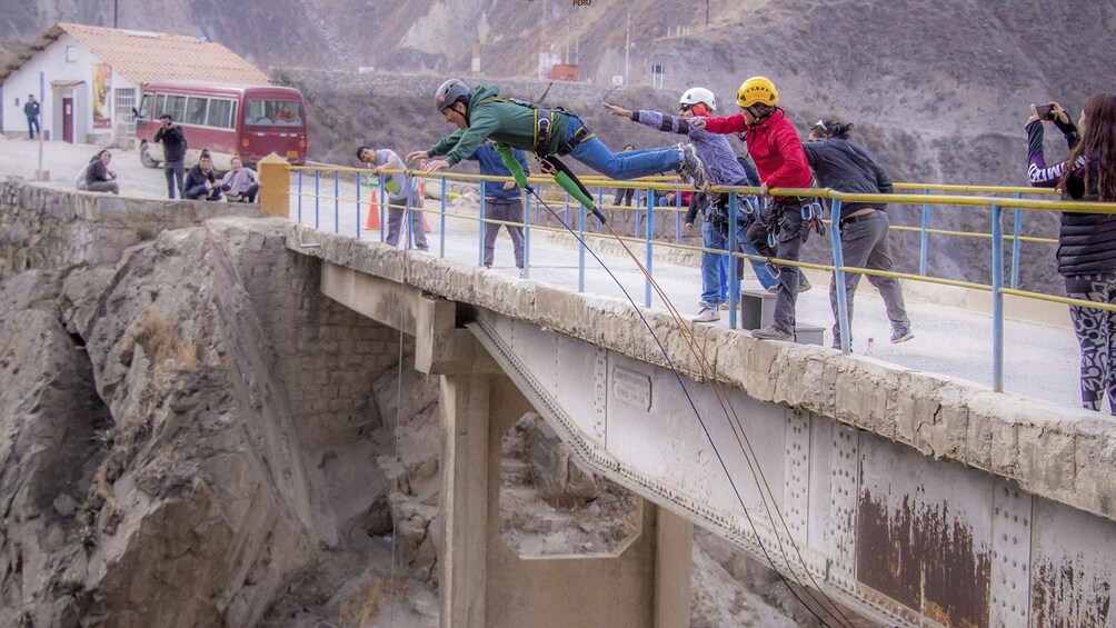 People rappelling down a bridge with a rocky landscape in the background. 5